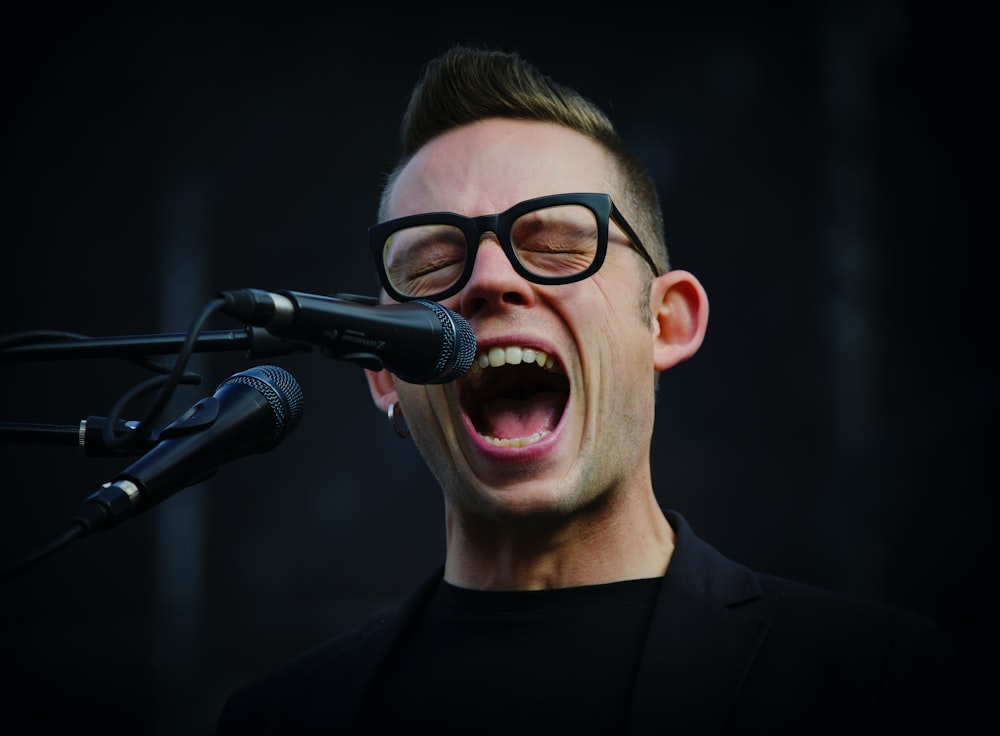 shallow focus photography of man shouting using microphone