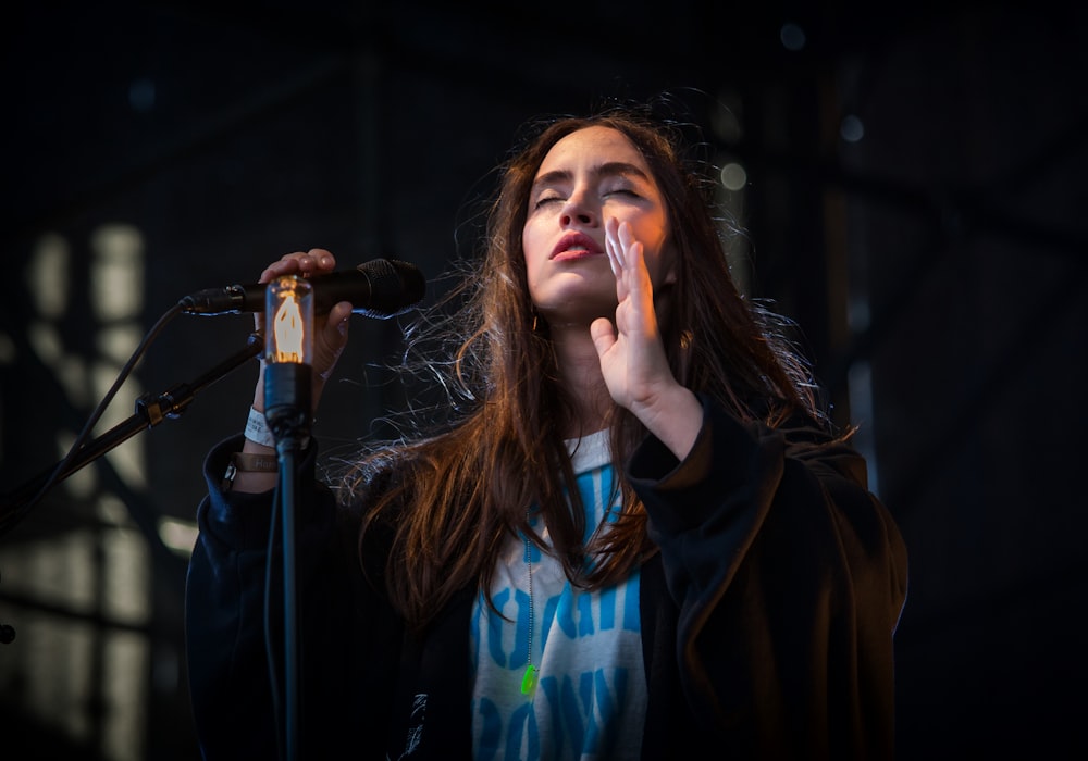 woman performing on stage with closed eyes and holding a microphone