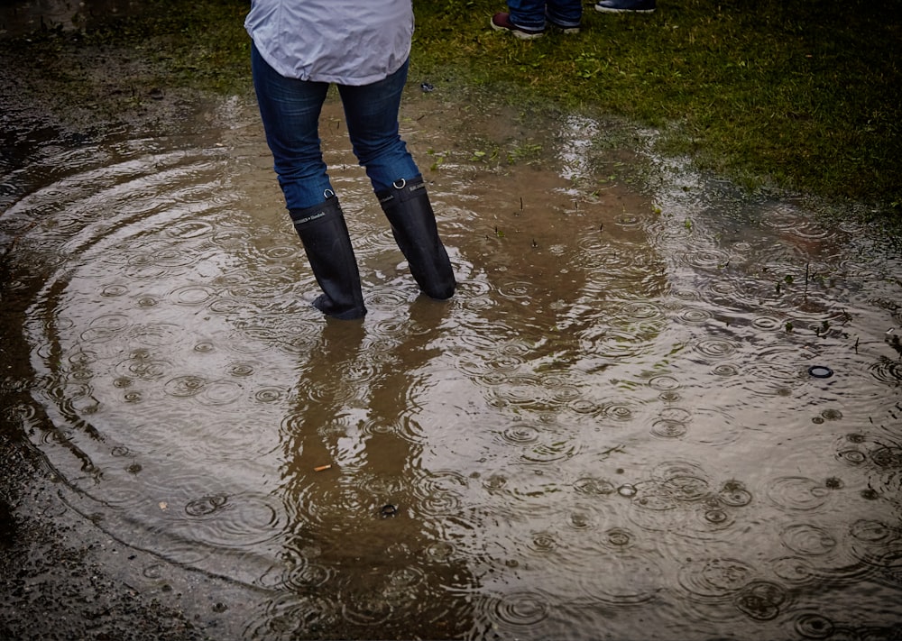 Persona con botas de lluvia de pie en el cuerpo de agua