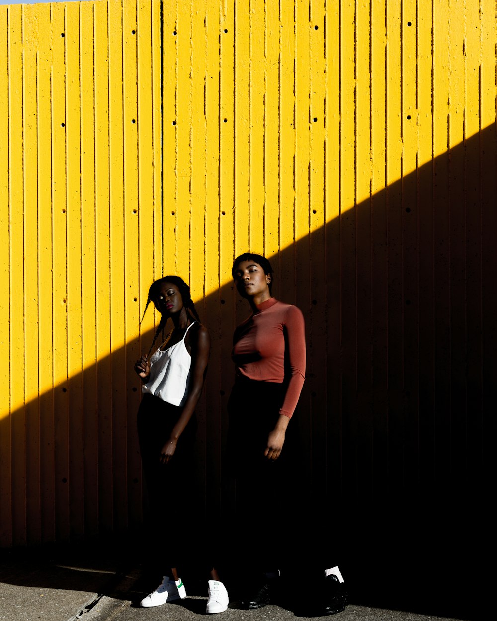 two women standing in front of yellow wall