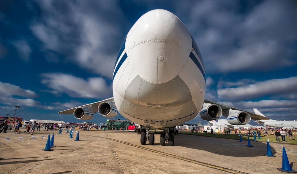 Selektive Fokusfotografie eines Flugzeugs unter weißen Wolken und blauem Himmel bei Tag