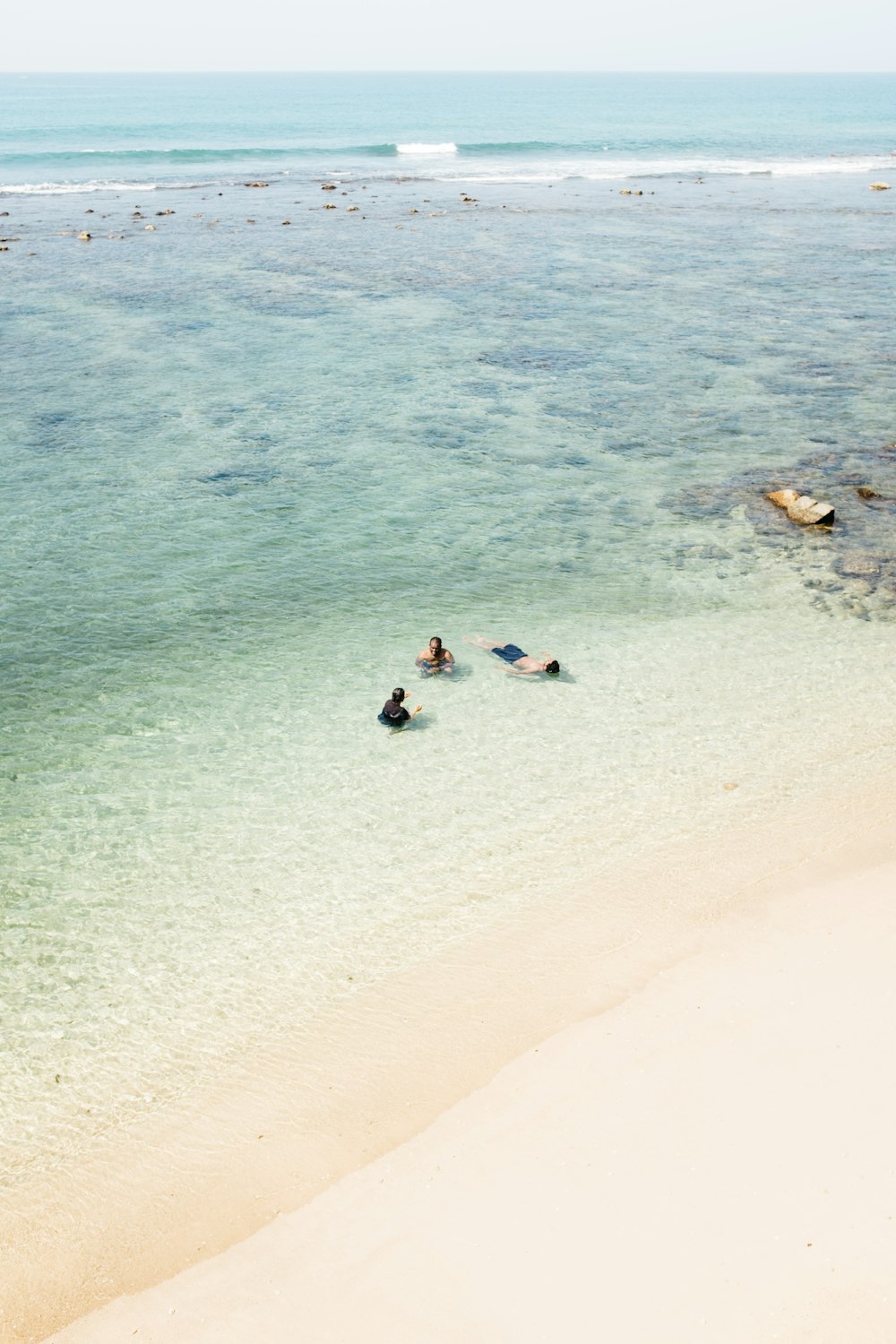 people swimming at beach near seashore