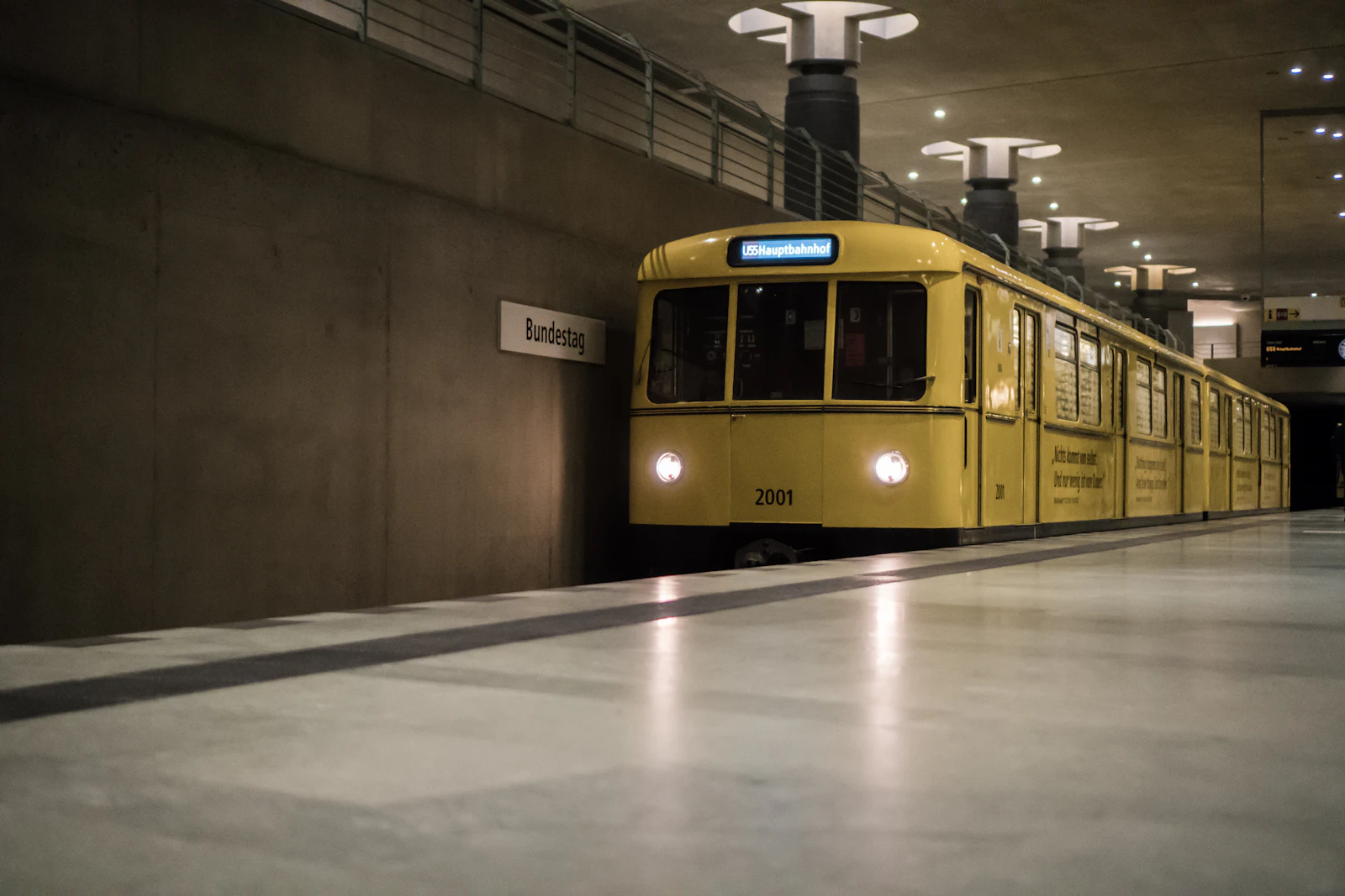 Berlin'de boş bir U-Bahn peronunda bekleyen sarı tren
