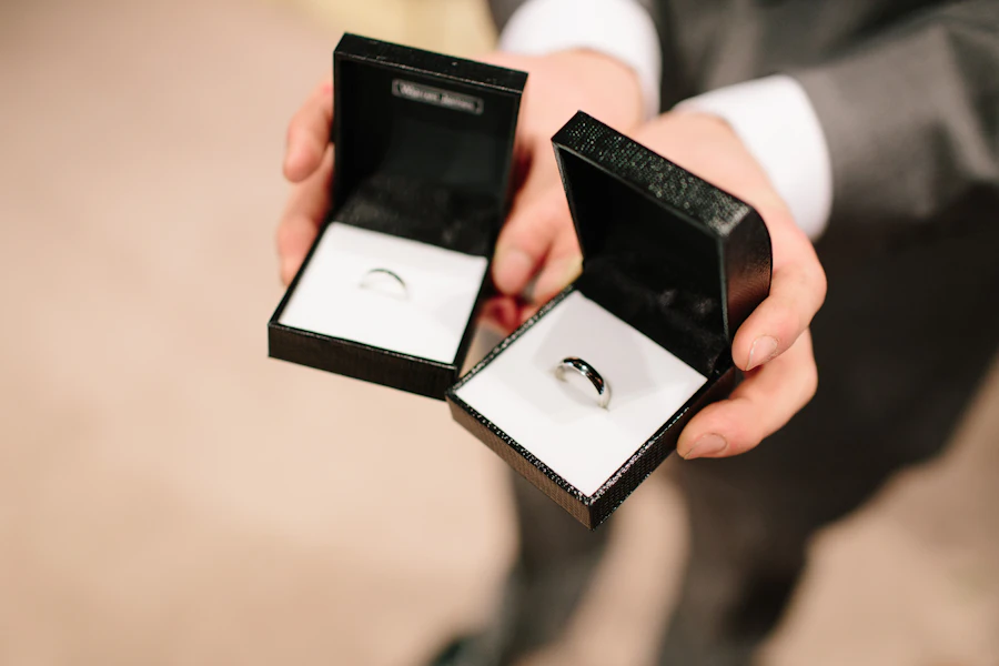 Hands holding two open ring boxes with diamond rings