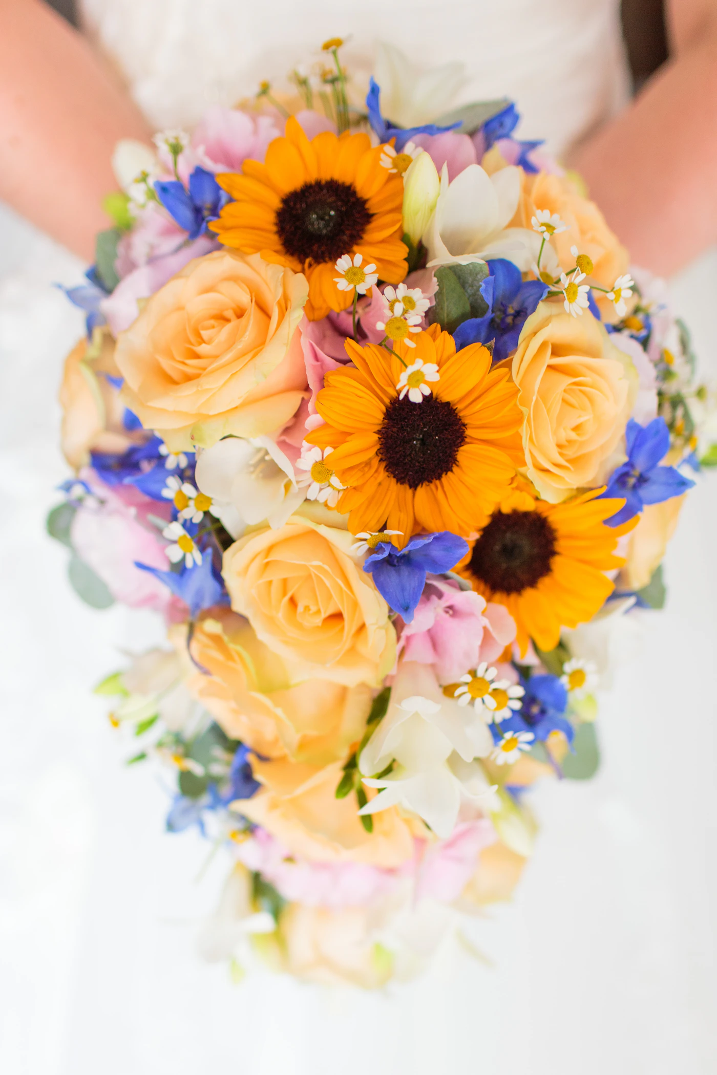 How to make your own bridal bouquet — A bride arranging fresh roses and greenery into a hand-tied bridal bouquet.