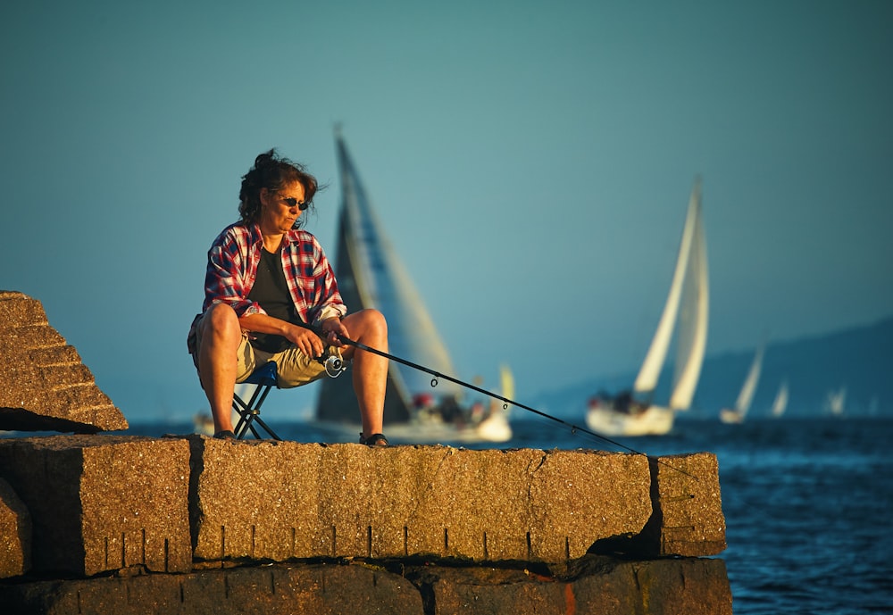 Mujer sentada sosteniendo caña de pescar negra esperando pescado