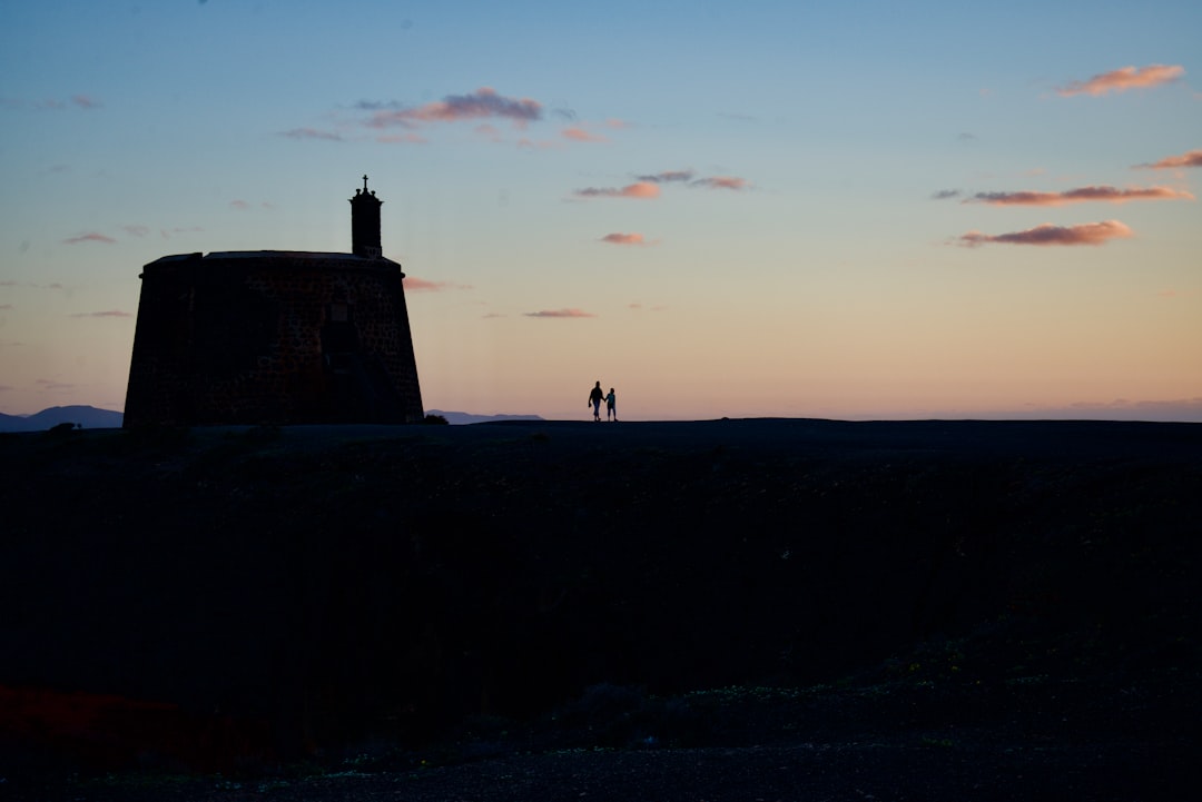 two people standing near structure silhouette photography