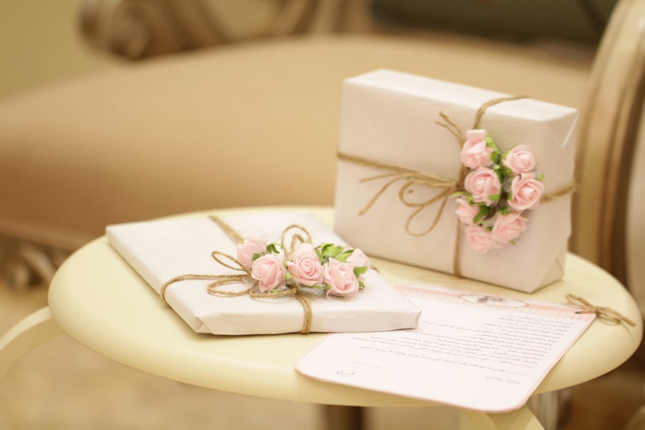 Anniversary gifts. Two rapped presents on a table. White wrapping pape and brown twine bows each with a small assortment of roses.