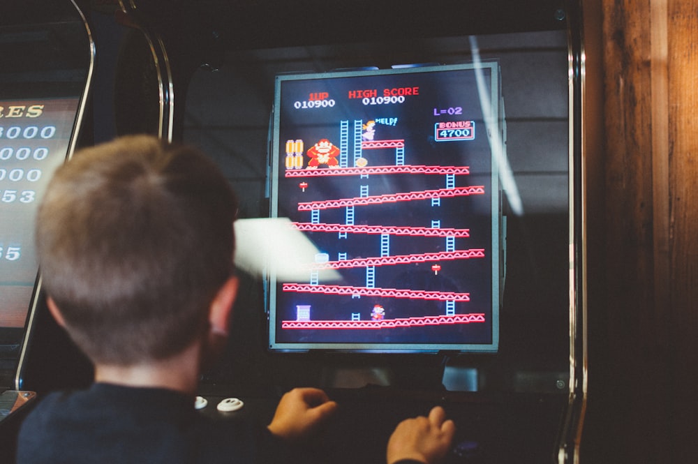 garçon jouant à la boîte d’arcade Donkey Kong