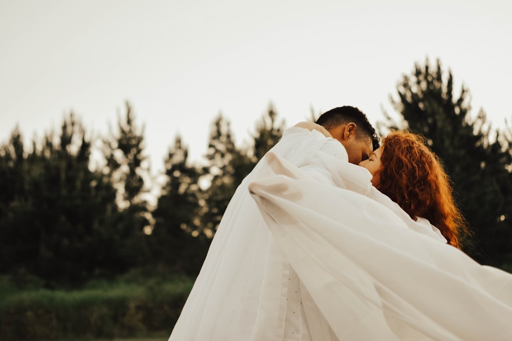 uomo che bacia la donna in tessuto durante il giorno