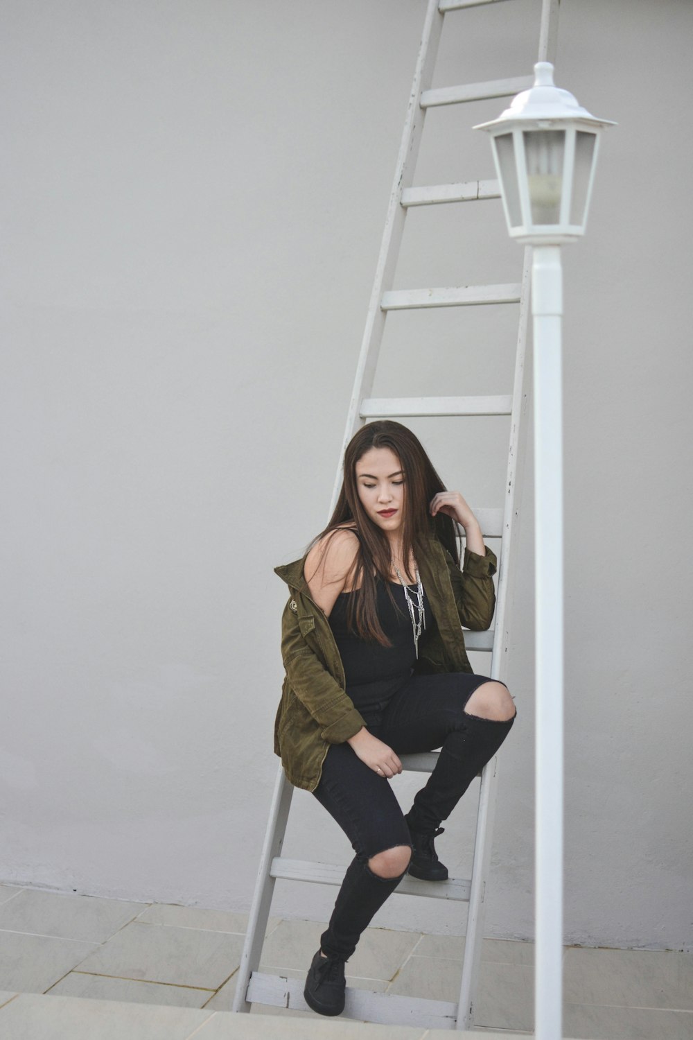 woman sitting on white steel ladder