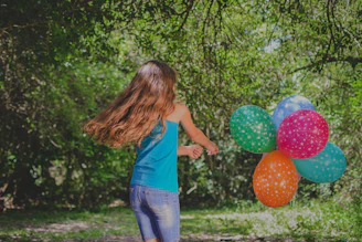 girl in blue top holding balloons