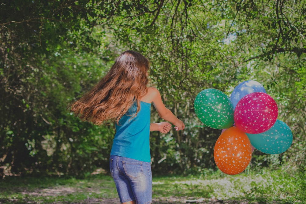 girl in blue top holding balloons