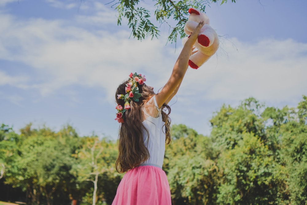 woman in white and pink dress holding bear plush toy