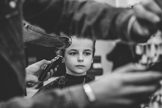 grayscale photo of boy having haircut