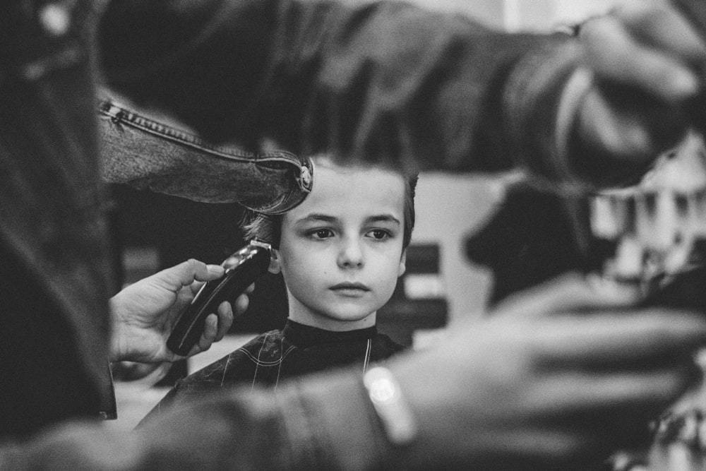 Foto en escala de grises de un niño que se corta el pelo