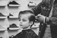 greyscale photo of boy having a haircut