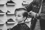 greyscale photo of boy having a haircut