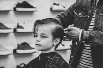greyscale photo of boy having a haircut