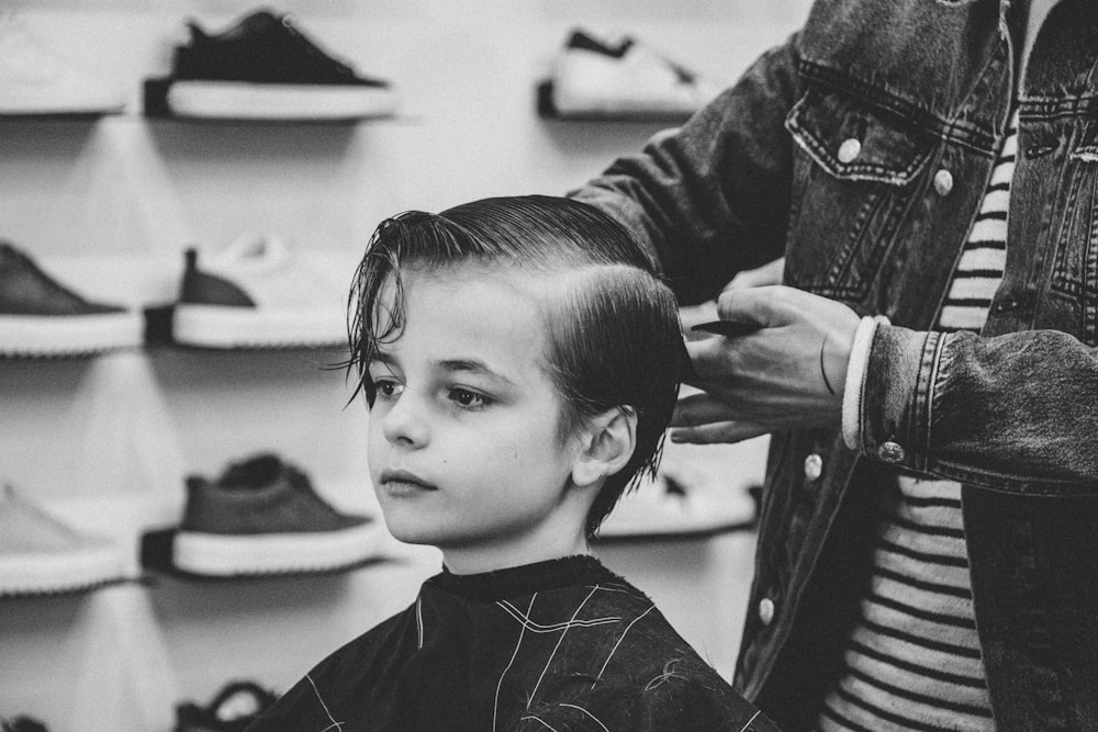 Foto en escala de grises de un chico cortándose el pelo