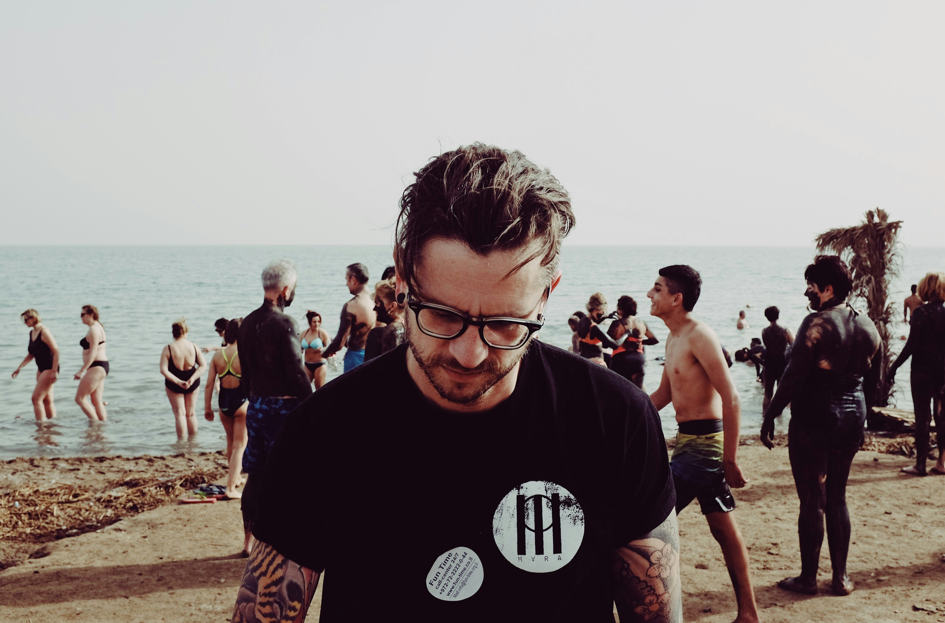 photo of man wearing eyeglasses standing on beach during daytime