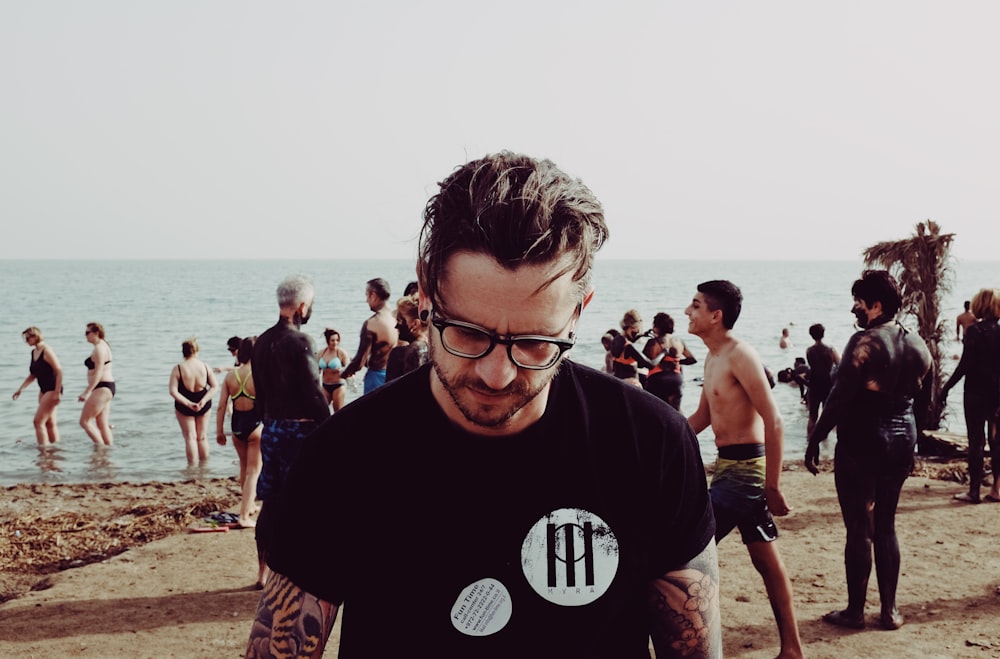 photo of man wearing eyeglasses standing on beach during daytime