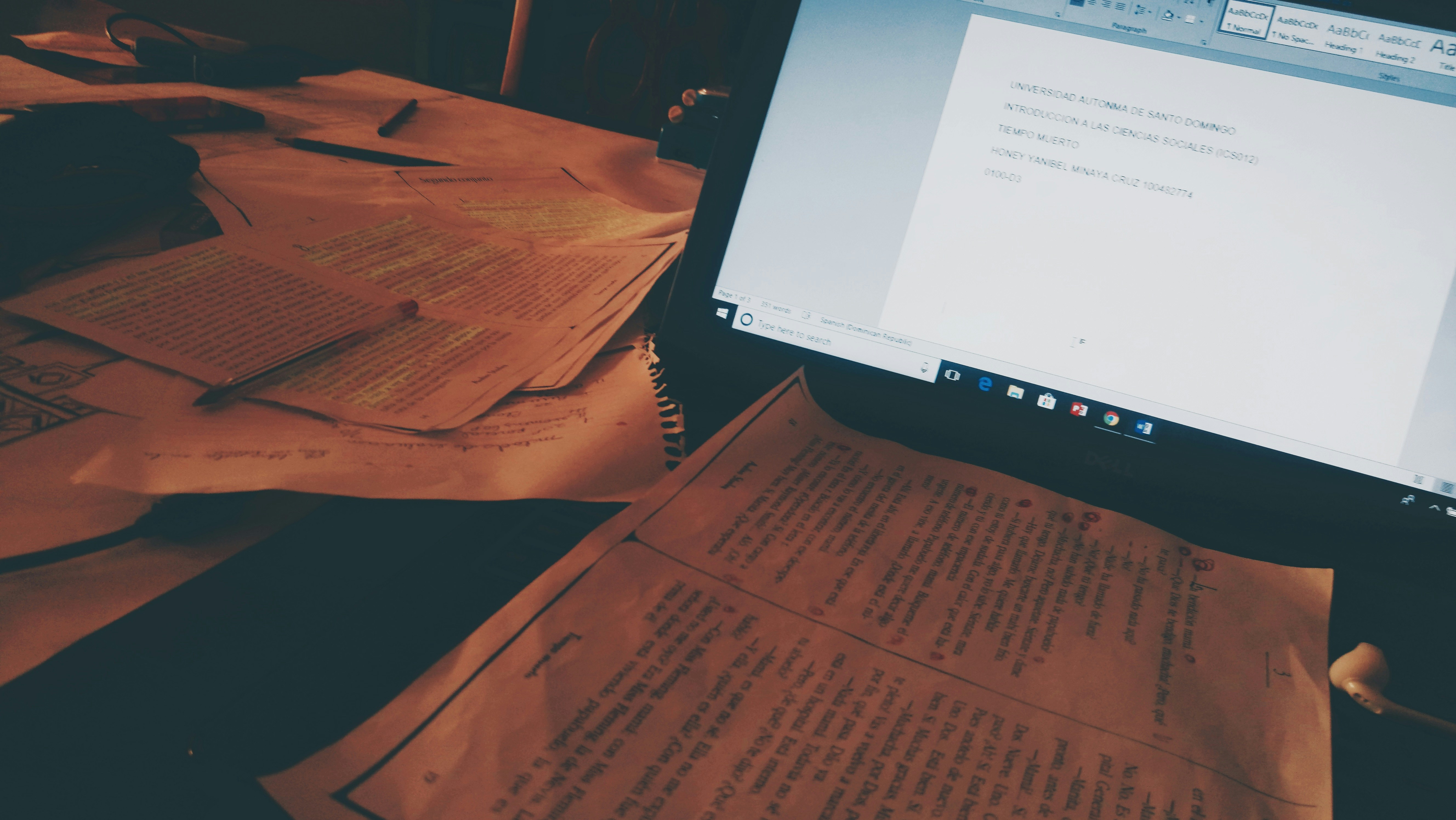 Person writing at a desk with papers and a laptop, focused and productive, warm ambient light