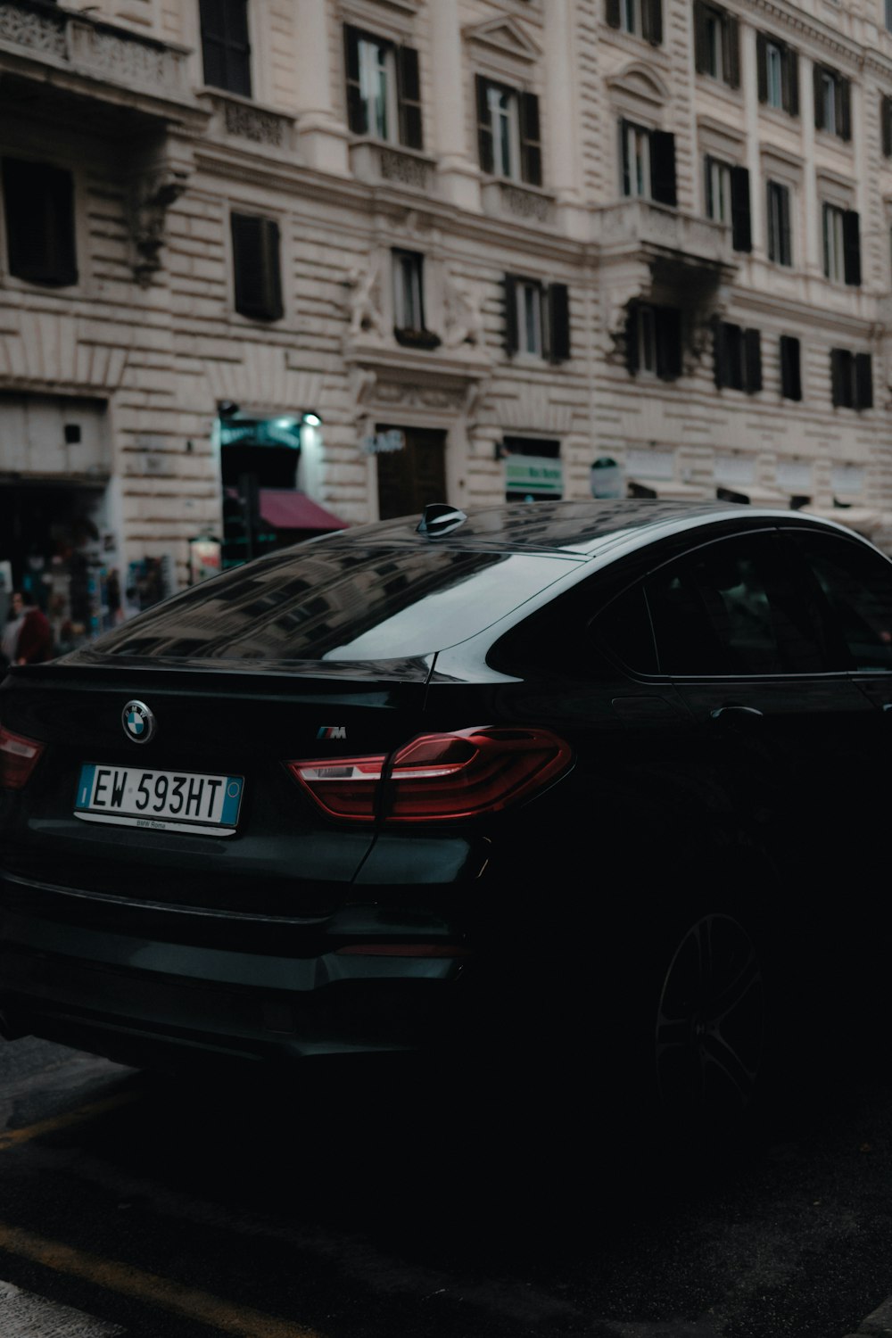 schwarze BMW-Limousine in der Nähe eines beigen Betongebäudes
