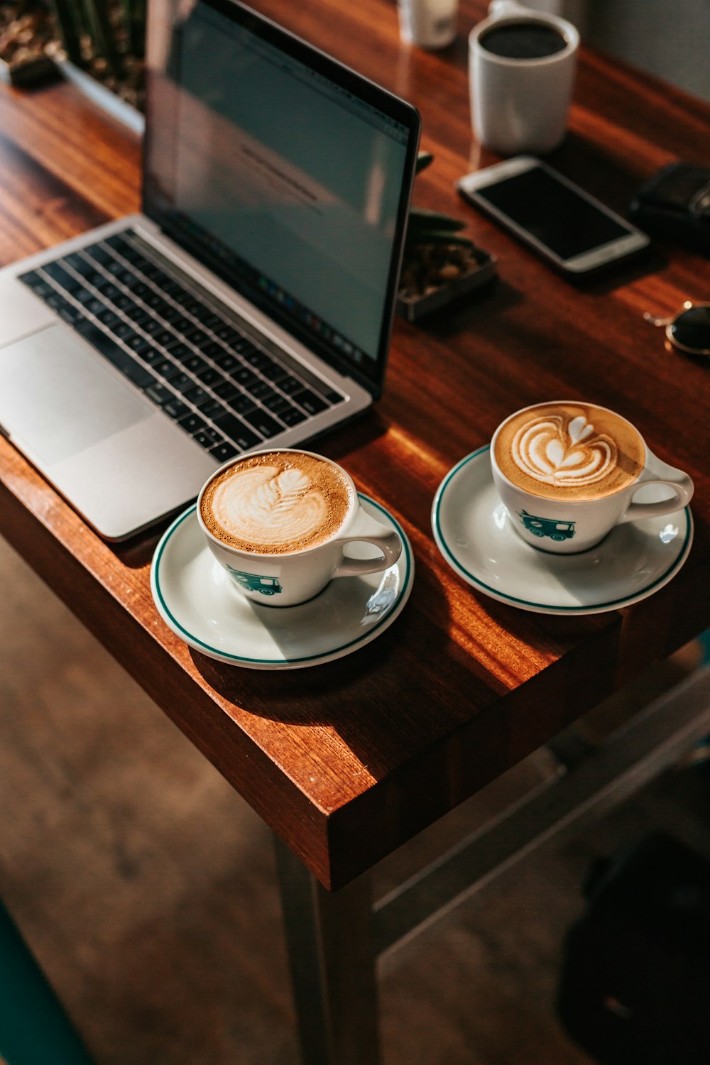 two white ceramic teacups near gray laptop computer