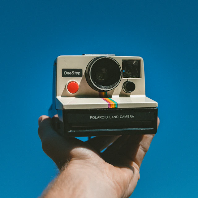 Person holding up a white and black Polaroid One Step instant camera