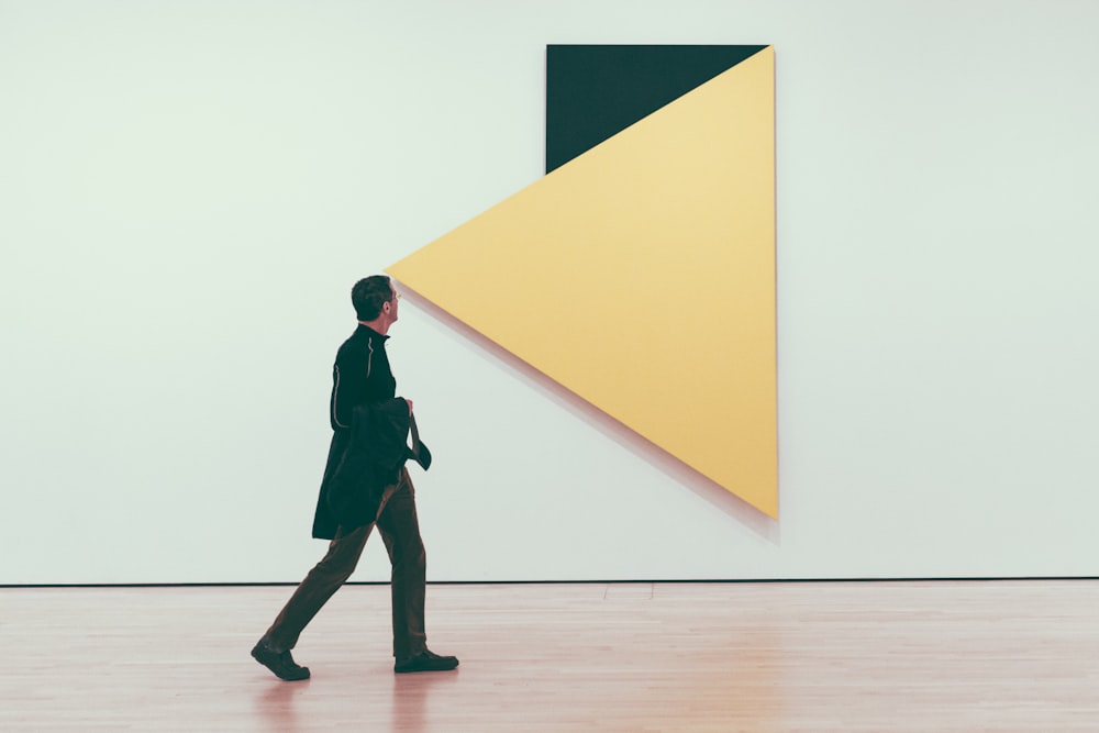 man looking on inverted yellow and green triangle wall art