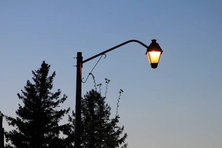 A warm-lit solar street lamp illuminating a quiet evening street.