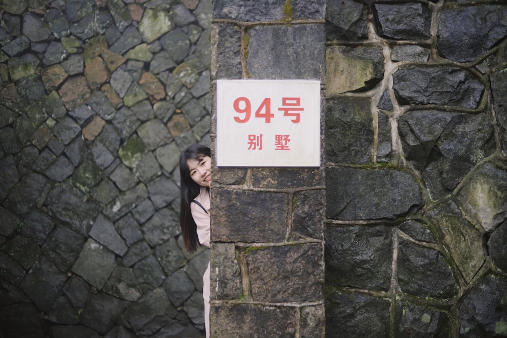 woman hiding behind a gray wall