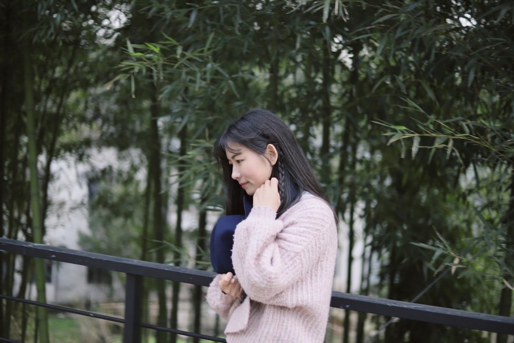 woman in pink sweatshirt standing near fence