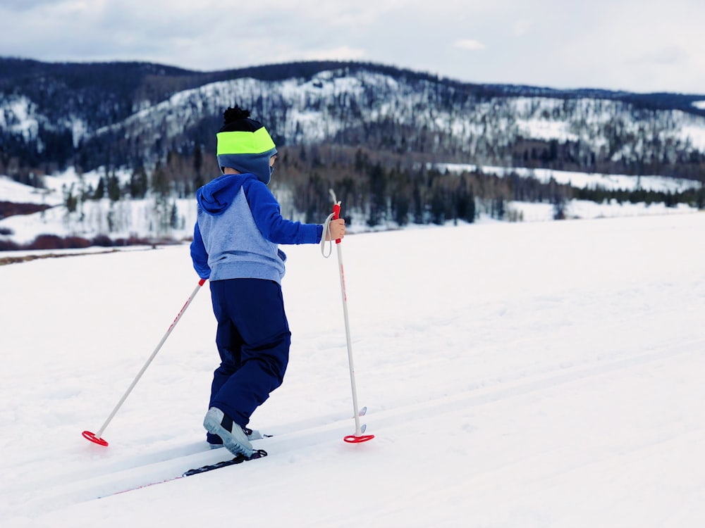 Junge im blauen und grauen Kapuzenpullover beim Skifahren
