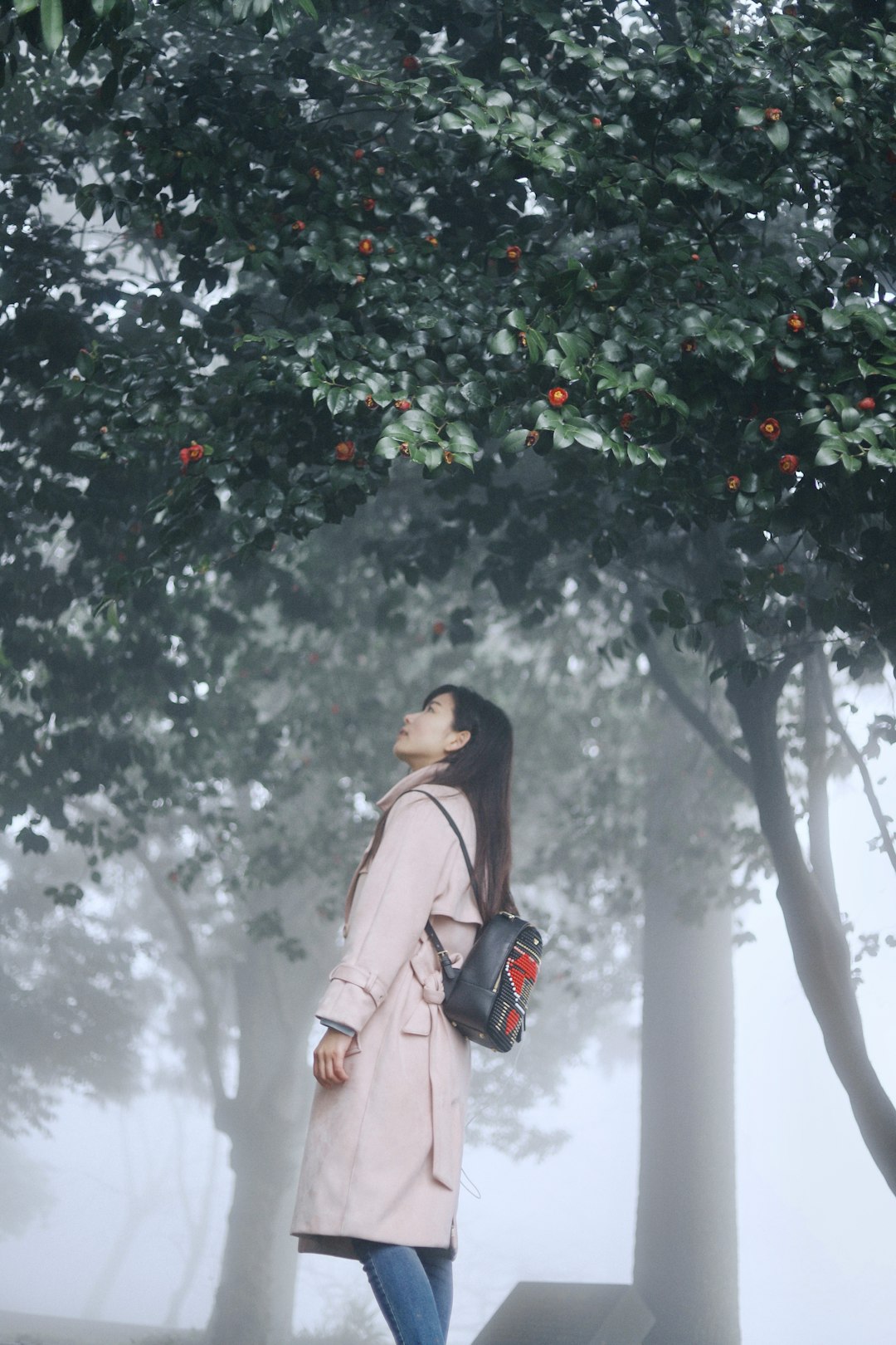woman wearing white coat standing near the trees