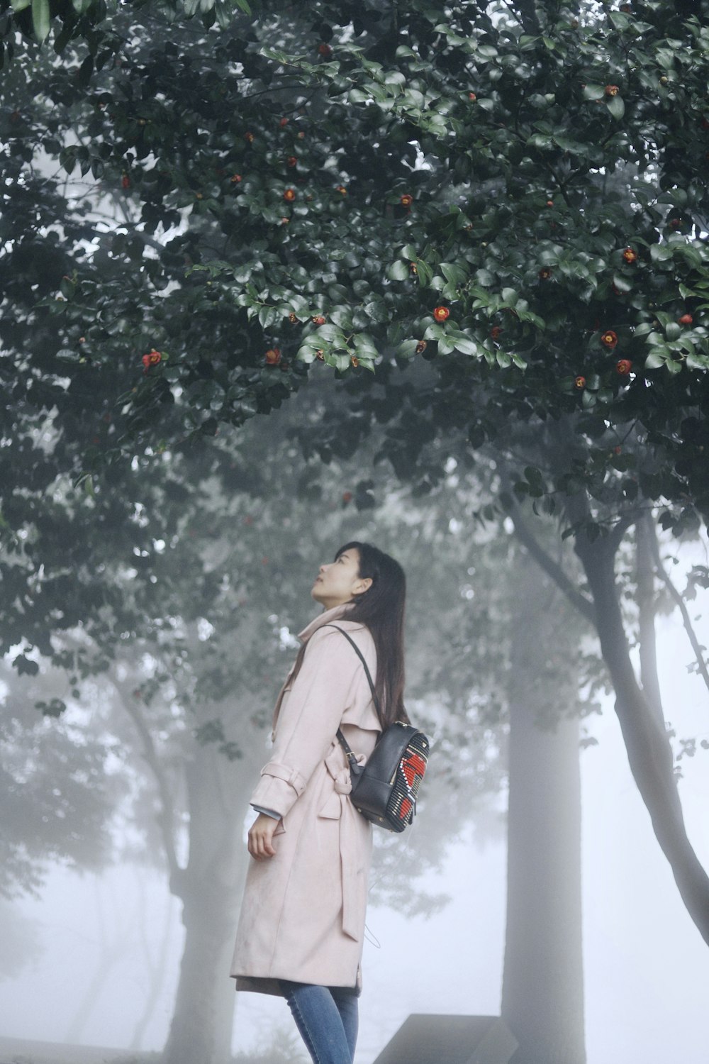 woman wearing white coat standing near the trees