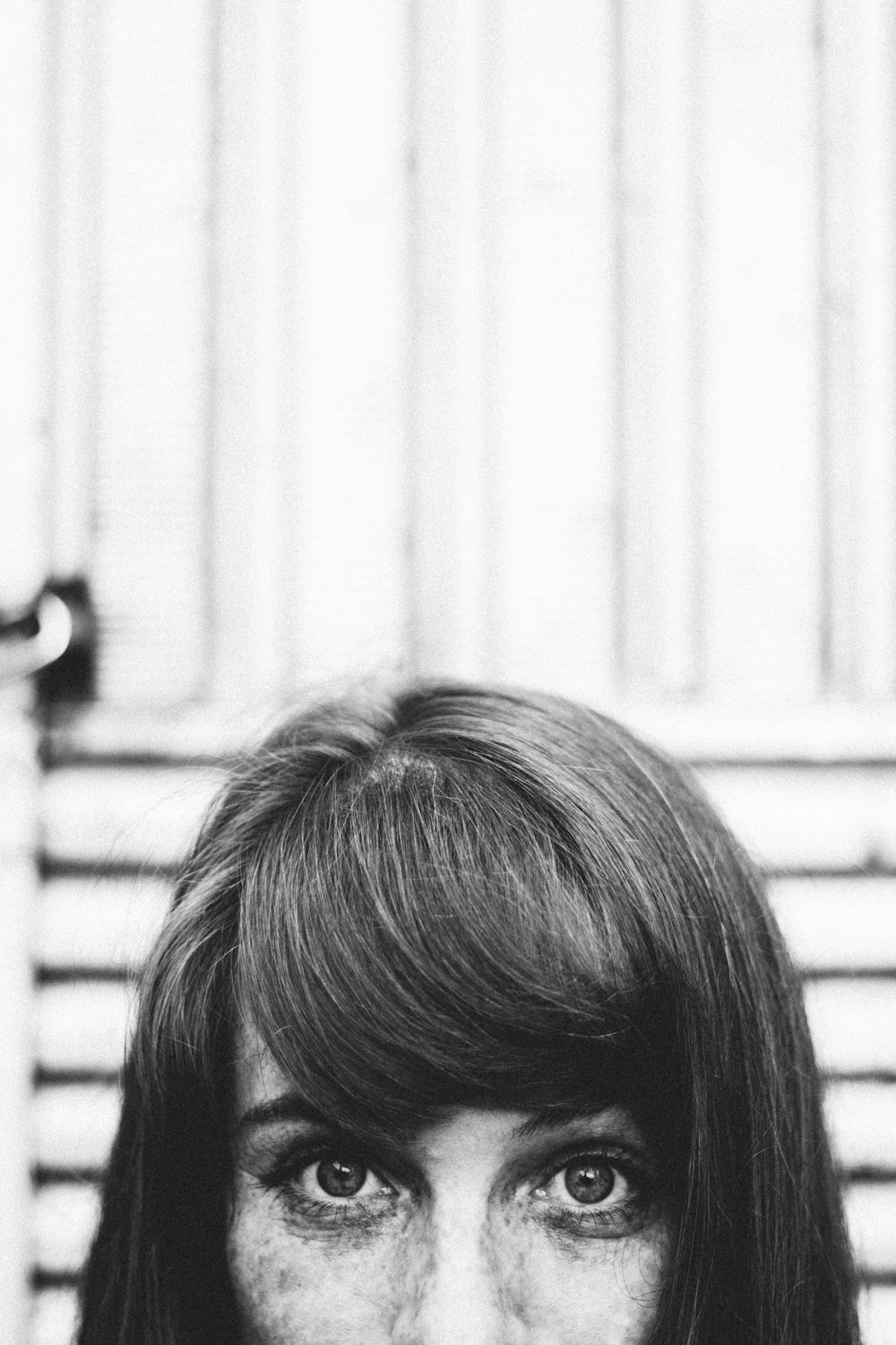 grayscale photography of woman standing near wall