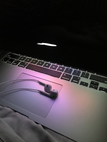 Close-up of sleek laptops and headphones with subtle glowing accents under warm lighting.