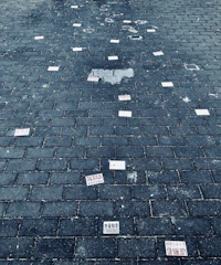 Close-up of hands arranging fragmented scripts on a cracked concrete floor.
