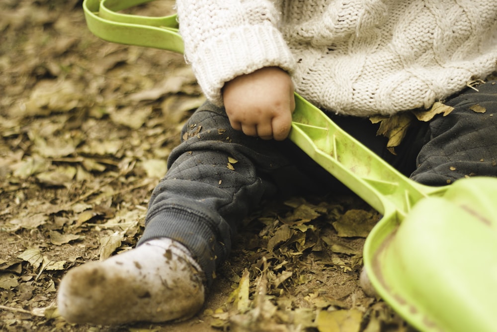 child holding green plastic shovel toy