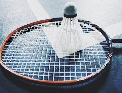 white shuttlecock on brown and black badminton racket placed on floor