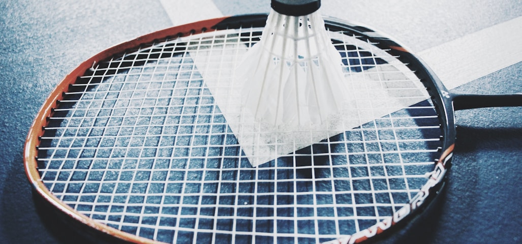 white shuttlecock on brown and black badminton racket placed on floor