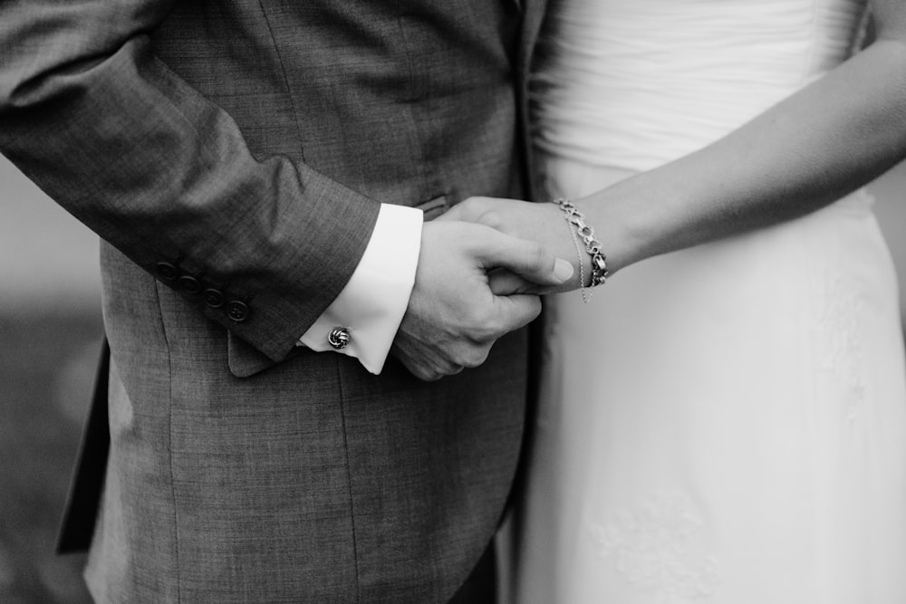 grayscale photo of man and woman holding each others hands