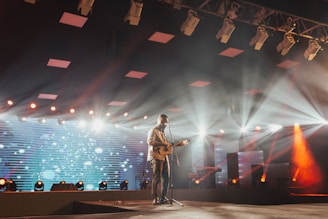 man standing on stage playing guitar