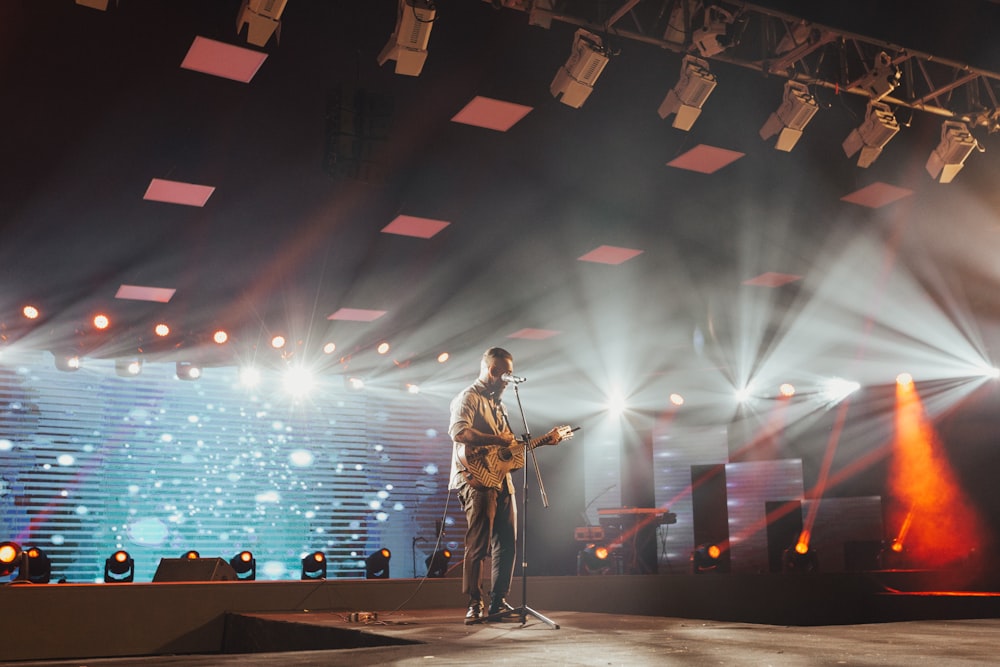 man standing on stage playing guitar