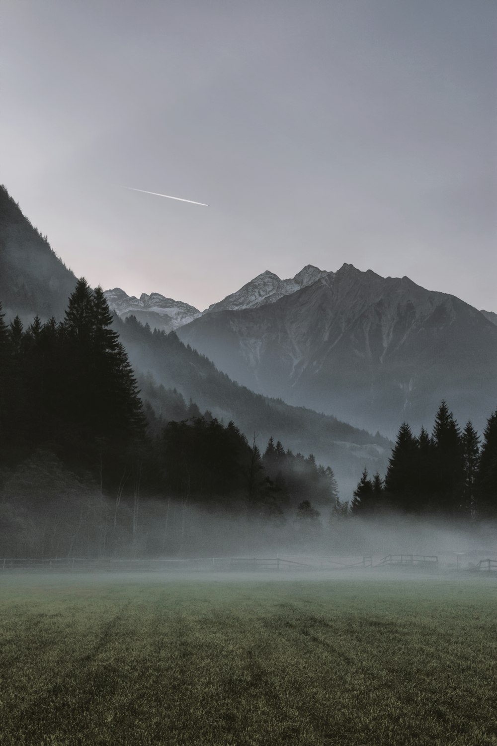 Foto de paisaje de montañas cubiertas de niebla y vista de estela de condensación
