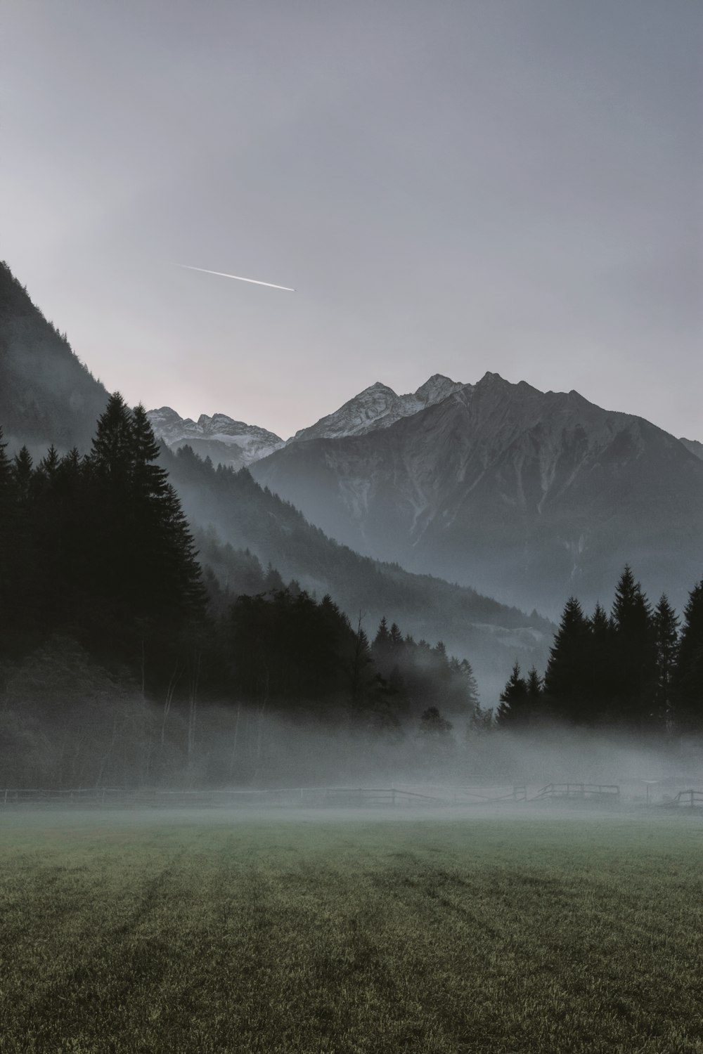 landscape photo of mountains covered by fogs and view of contrail