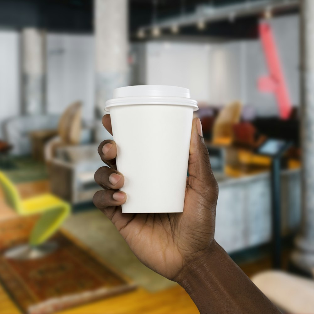 person holding white disposable cup