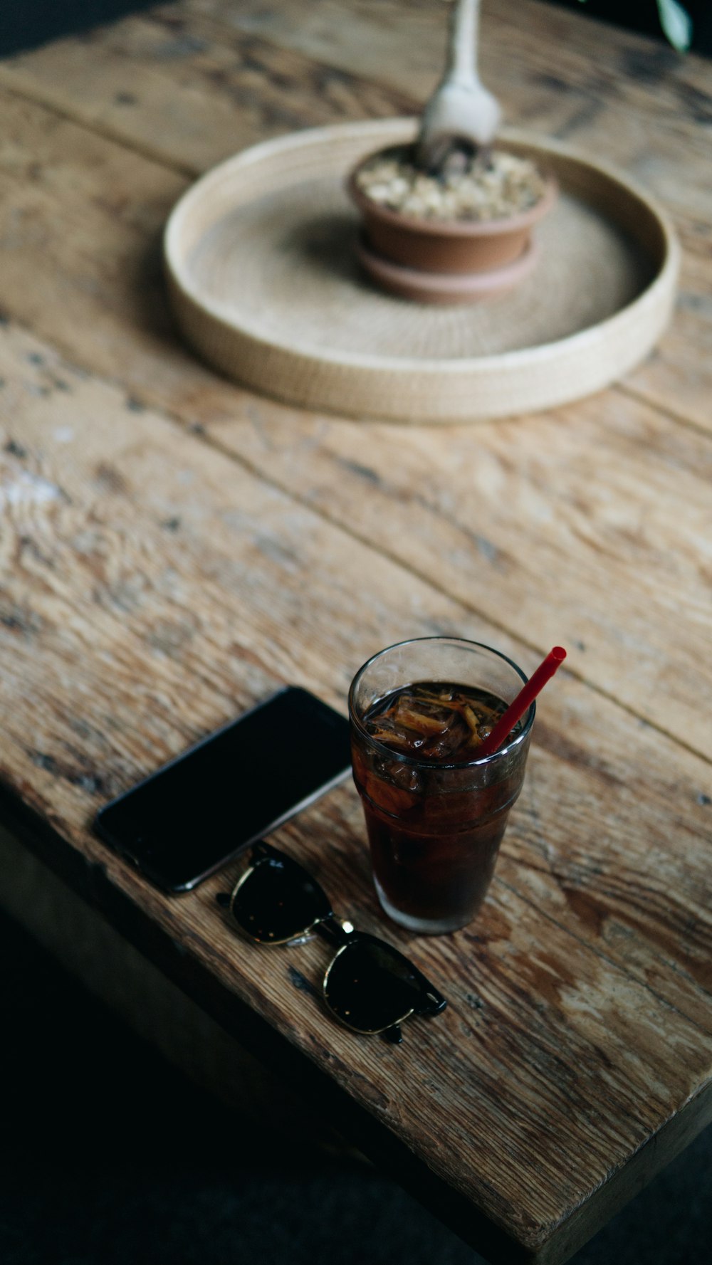 verre à boire transparent à côté d’un smartphone noir sur une table en bois marron